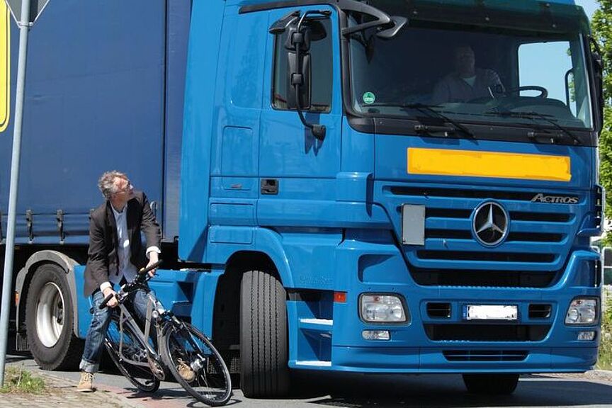 Rechtsabbiegender LKW Ein rechtsabbiegender LKW mit einem Radfahrer, der fast mit ihm kollidiert.